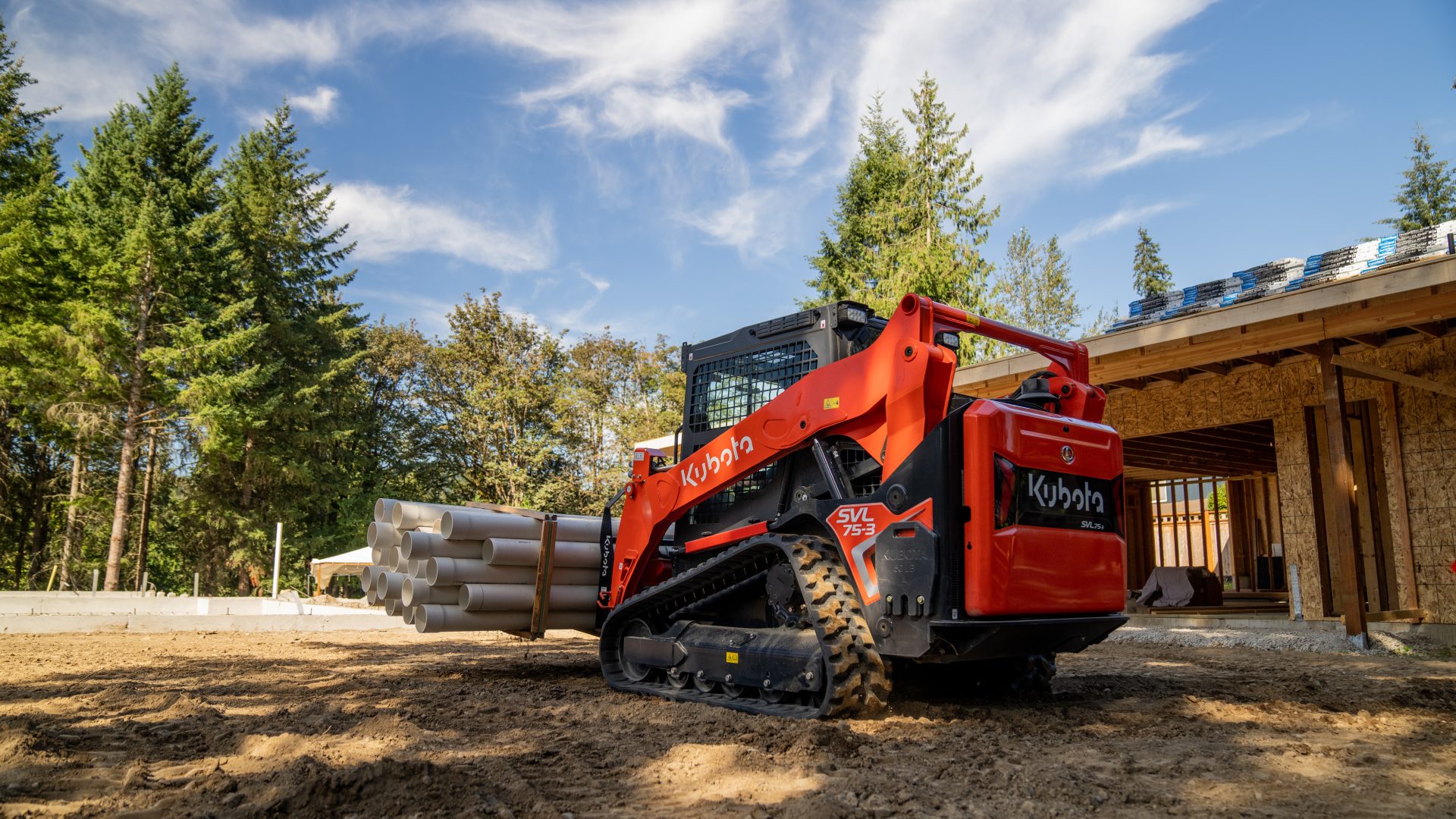 Kubota SVL75-3 skid steer in forest lifting wood